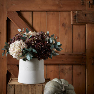 Autumn Flowers in white post against wooden door with pumpkin ornament.