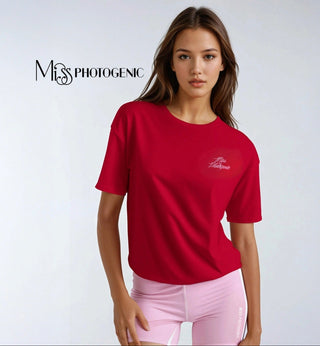 Woman wearing a red t-shirt with a logo on a white background, featuring the brand 'Miss Photogenic'.